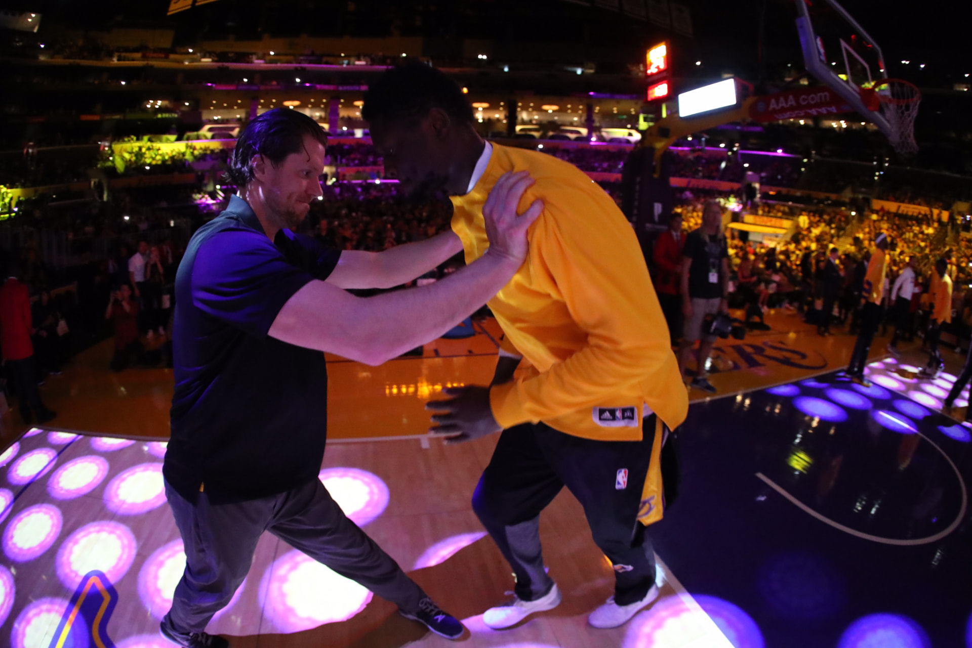 Sean Light guiding a Los Angeles Lakers player onto the floor before tip-off.